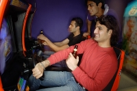 Young men in amusement arcade playing video games - Asia Images Group