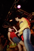 Young people dancing in night club, couple in the foreground - Asia Images Group