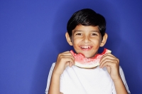 Boy looking at camera, holding half eaten slice of watermelon - Asia Images Group