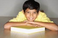 Boy lying on floor, leaning on book - Asia Images Group