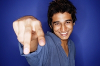 Man against blue background, making hand sign - Asia Images Group