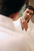 Man in bathrobe looking at himself in mirror - Asia Images Group