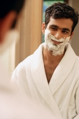 Man looking in mirror having cream on face - Asia Images Group