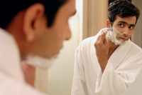 Man in bathroom, shaving his face - Asia Images Group