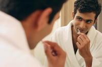 Man looking in bathroom mirror, brushing his teeth - Asia Images Group