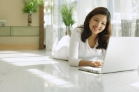Woman at home using laptop, smiling - Asia Images Group