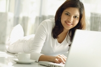 Woman at home with laptop, smiling at camera - Asia Images Group
