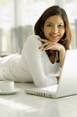 Woman smiling at camera, laptop open in front of her - Asia Images Group