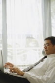 Businessman reclining on chair, using laptop - Asia Images Group