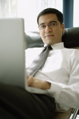Businessman with laptop, looking at camera - Asia Images Group