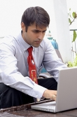 Businessman sitting outdoors, using laptop - Asia Images Group