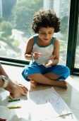 Girl sitting on floor with crayons and paper, fathers hands in foreground - Asia Images Group