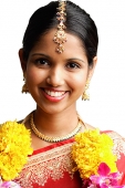 Woman in sari wearing a garland, smiling at camera, head shot - Asia Images Group