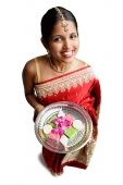 Woman in sari, holding plate of Indian cakes, smiling at camera - Asia Images Group
