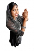 Woman in gray sari standing against white background, hands together - Asia Images Group