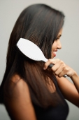 Woman brushing her hair, side view - Asia Images Group