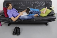 Man sitting on sofa using laptop - Asia Images Group