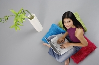 Woman sitting on floor with laptop, looking up at camera - Asia Images Group