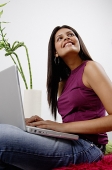 Woman with laptop, smiling, looking away - Asia Images Group