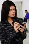 Businesswoman using PDA, people in the background - Asia Images Group