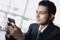 Young businessman using mobile phone, text messaging - Asia Images Group