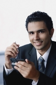 Young businessman with mobile phone, smiling at camera - Asia Images Group