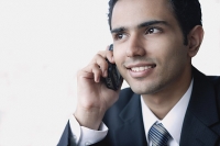 Young businessman using mobile phone, smiling - Asia Images Group