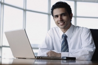 Young businessman with laptop, smiling at camera - Asia Images Group