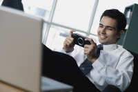 Young businessman playing with Playstation Portable - Asia Images Group