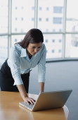 Businesswoman standing and using laptop - Asia Images Group