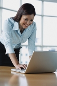 Businesswoman using laptop, leaning on table - Asia Images Group