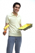 Man holding paint roller and paint tray - Asia Images Group