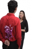 Man holding flowers behind his back, facing woman - Asia Images Group