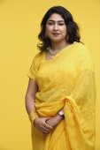 Woman in yellow sari standing against yellow background - Asia Images Group