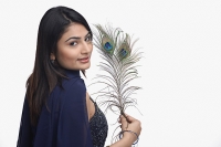 Woman looking at camera, holding peacock feather - Asia Images Group