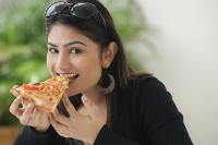 Woman eating a slice of pizza - Asia Images Group