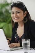 Woman using laptop, smiling at camera - Asia Images Group