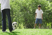 A father and son play soccer together - Asia Images Group