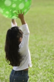 A small girl plays with a green ball - Asia Images Group