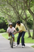 A father teaches his son to ride a bike - Asia Images Group