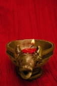 A golden ox candle holder and candle - Asia Images Group