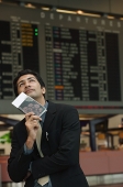Man holding passport on his chin in the airport - Asia Images Group