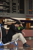 Man waiting in departure lounge at airport - Asia Images Group