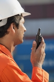 Man in work uniform using walkie talkie - Asia Images Group