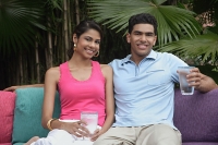 Couple sitting on sofa outdoors, smiling at camera - Asia Images Group