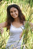 Young woman in high grass smiling at camera - Asia Images Group