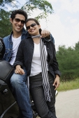 Young couple with motorbike smiling at camera - Asia Images Group