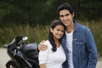Young couple with motorbike smiling at camera - Asia Images Group