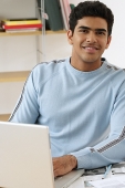 Young man with laptop smiling at camera - Asia Images Group