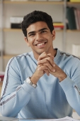 Young man sitting at desk and smiling at camera - Asia Images Group